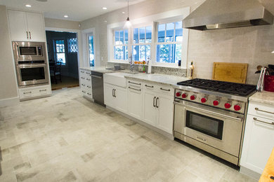 Kitchen - large traditional single-wall porcelain tile kitchen idea in Other with a farmhouse sink, shaker cabinets, white cabinets, granite countertops, beige backsplash, subway tile backsplash, stainless steel appliances and a peninsula