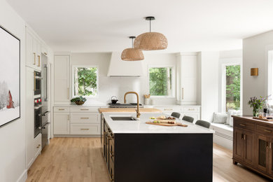 Large transitional l-shaped light wood floor eat-in kitchen photo in Burlington with an undermount sink, shaker cabinets, quartzite countertops, white backsplash, stone slab backsplash, stainless steel appliances, an island and white countertops