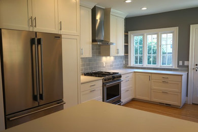 Enclosed kitchen - mid-sized craftsman u-shaped light wood floor and brown floor enclosed kitchen idea in Portland with an undermount sink, shaker cabinets, white cabinets, quartz countertops, blue backsplash, ceramic backsplash, stainless steel appliances, no island and gray countertops