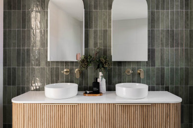 Inspiration for a mid-sized contemporary kids bathroom in Sydney with light wood cabinets, green tile, green walls, white benchtops, a double vanity, a floating vanity, flat-panel cabinets, terrazzo floors, a vessel sink and grey floor.