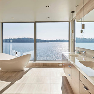 Large trendy master beige tile and porcelain tile porcelain floor and beige floor freestanding bathtub photo in Seattle with flat-panel cabinets, medium tone wood cabinets, a one-piece toilet, beige walls, an undermount sink, limestone countertops and beige countertops