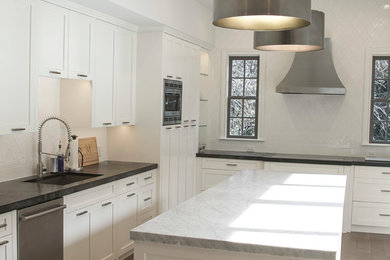 Large transitional u-shaped medium tone wood floor eat-in kitchen photo in Austin with an undermount sink, shaker cabinets, white cabinets, marble countertops, white backsplash, ceramic backsplash, stainless steel appliances and an island