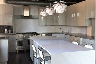 Kitchen - large industrial u-shaped black floor kitchen idea in Chicago with an undermount sink, flat-panel cabinets, white cabinets, marble countertops, white backsplash, stone slab backsplash, stainless steel appliances and an island