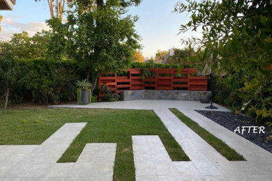 Photo of a mid-sized contemporary full sun backyard stone and wood fence landscaping.