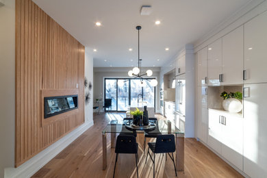 Foto di una sala da pranzo aperta verso la cucina minimalista di medie dimensioni con pareti beige, parquet chiaro, camino sospeso e pavimento beige
