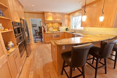 Mid-sized transitional light wood floor enclosed kitchen photo in Denver with an undermount sink, shaker cabinets, light wood cabinets, white backsplash, subway tile backsplash, stainless steel appliances and a peninsula