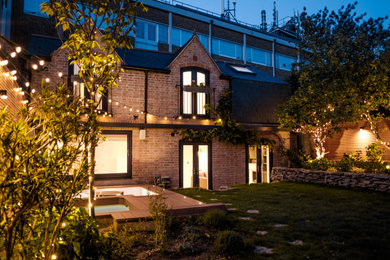 This is an example of a small and multi-coloured traditional two floor brick tiny house in London with a mansard roof and a tiled roof.