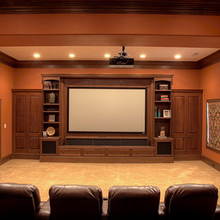 Idée de décoration pour une grande salle de cinéma tradition fermée avec un mur orange, moquette, un écran de projection et un sol beige.