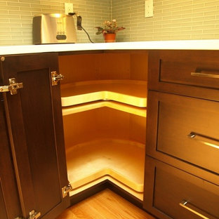 Eat-in kitchen - mid-sized transitional l-shaped light wood floor and beige floor eat-in kitchen idea in New York with a farmhouse sink, shaker cabinets, brown cabinets, quartz countertops, blue backsplash, glass tile backsplash, stainless steel appliances and an island