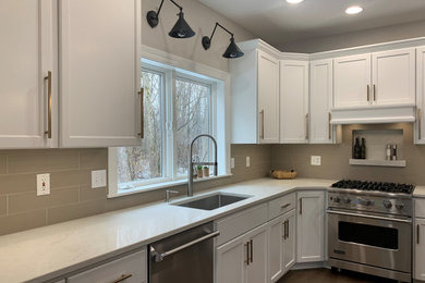 Kitchen - large transitional l-shaped medium tone wood floor kitchen idea in Milwaukee with recessed-panel cabinets, white cabinets, quartz countertops, beige backsplash, stainless steel appliances, an island and white countertops
