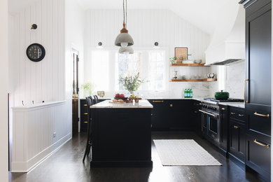 Example of a mid-sized transitional l-shaped dark wood floor and brown floor kitchen pantry design in Chicago with a farmhouse sink, shaker cabinets, black cabinets, marble countertops, white backsplash, marble backsplash, paneled appliances and an island