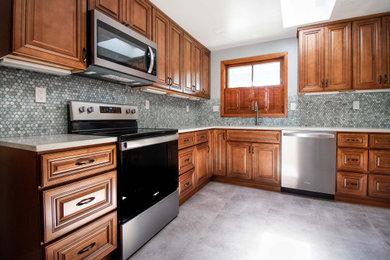 Mid-sized transitional l-shaped vinyl floor and gray floor enclosed kitchen photo in Portland with an undermount sink, beaded inset cabinets, medium tone wood cabinets, quartz countertops, blue backsplash, glass tile backsplash, stainless steel appliances, no island and white countertops