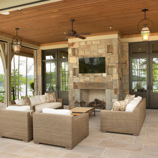 This is an example of a large traditional backyard patio in Other with a fire feature, natural stone pavers and a roof extension.