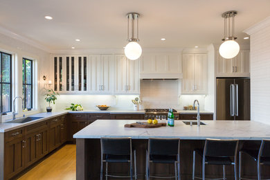 Example of a large transitional l-shaped light wood floor open concept kitchen design with an undermount sink, shaker cabinets, dark wood cabinets, marble countertops, white backsplash, paneled appliances and a peninsula