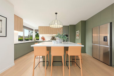 Photo of a large contemporary kitchen in Sydney with a double-bowl sink, green cabinets, quartz benchtops, white splashback, engineered quartz splashback, stainless steel appliances, light hardwood floors, with island, brown floor and white benchtop.