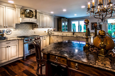 Inspiration for a mid-sized timeless u-shaped medium tone wood floor and brown floor kitchen remodel in Richmond with an undermount sink, raised-panel cabinets, beige cabinets, marble countertops, gray backsplash, subway tile backsplash, stainless steel appliances and an island