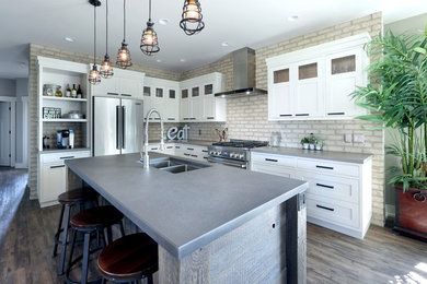 Photo of an industrial kitchen in Grand Rapids with an undermount sink, recessed-panel cabinets, white cabinets, concrete benchtops, stainless steel appliances, dark hardwood floors and with island.