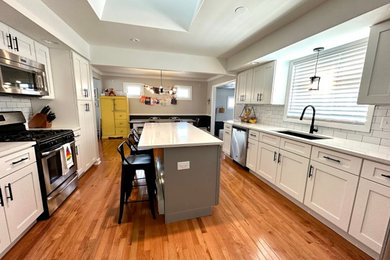 Example of a mid-sized minimalist medium tone wood floor kitchen design in Other with shaker cabinets, white cabinets, quartzite countertops and an island