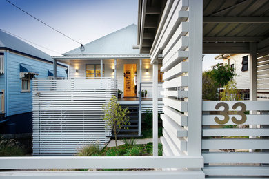 Large transitional two-storey white house exterior in Brisbane with wood siding, a hip roof and a metal roof.