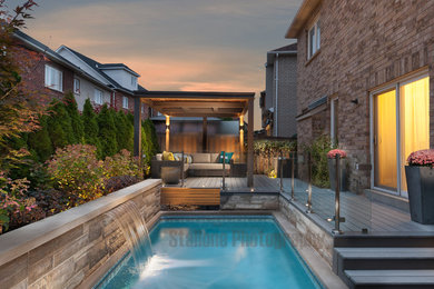 Example of a minimalist backyard rectangular natural pool fountain design in Toronto