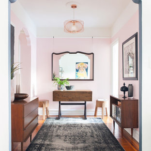 Inspiration för en eklektisk foajé, med rosa väggar, mellanmörkt trägolv och brunt golv