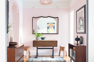 Photo of an eclectic foyer in New York with pink walls, medium hardwood floors and brown floor.