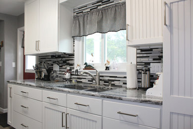 Kitchen - galley vinyl floor and gray floor kitchen idea in Grand Rapids with white cabinets, quartzite countertops, metallic backsplash and stainless steel appliances