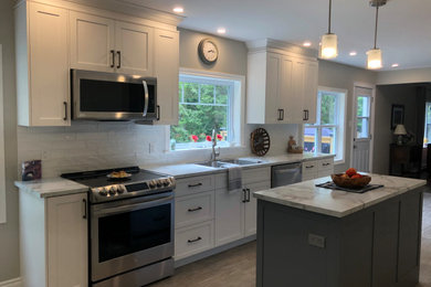 Eat-in kitchen - mid-sized farmhouse galley vinyl floor and gray floor eat-in kitchen idea in Other with a double-bowl sink, shaker cabinets, white cabinets, laminate countertops, white backsplash, ceramic backsplash, stainless steel appliances, an island and white countertops
