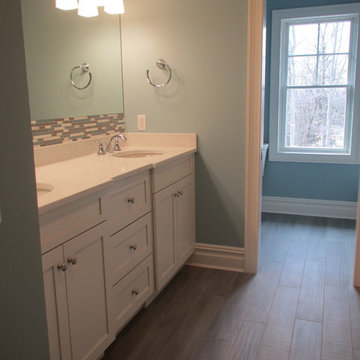 Bathroom with Double Vanity, Mosaic Tile Backsplash, and Wood-Pattern Floor Tile