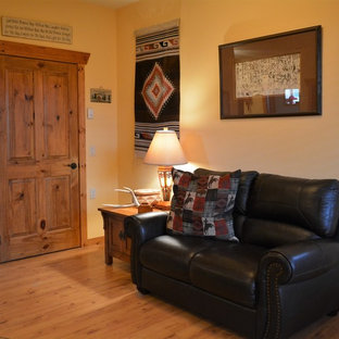 Mittelgroßes, Abgetrenntes Mediterranes Wohnzimmer mit gelber Wandfarbe, Laminat, Kaminofen, verputztem Kaminsims und freistehendem TV in Denver