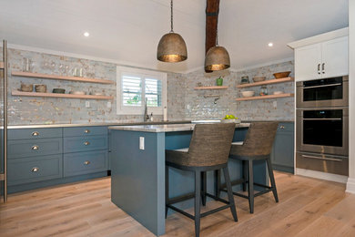 Example of a mid-sized transitional u-shaped light wood floor, beige floor and exposed beam eat-in kitchen design in Other with a double-bowl sink, shaker cabinets, blue cabinets, granite countertops, beige backsplash, porcelain backsplash, stainless steel appliances, an island and beige countertops