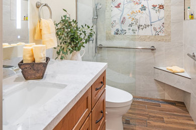 Bathroom - small eclectic white tile and porcelain tile porcelain tile, brown floor and single-sink bathroom idea in Other with shaker cabinets, medium tone wood cabinets, a one-piece toilet, beige walls, an undermount sink, quartz countertops and white countertops