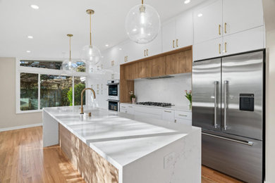 Inspiration for a medium tone wood floor, brown floor and wood ceiling kitchen remodel in Seattle with a drop-in sink, white cabinets, white backsplash, marble backsplash, stainless steel appliances, an island and white countertops