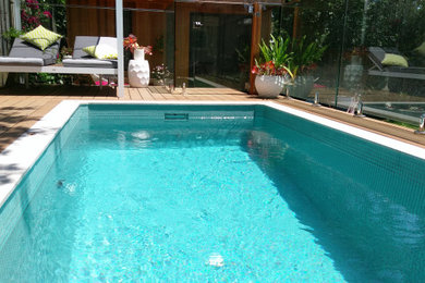Design ideas for a mid-sized beach style backyard rectangular aboveground pool in Other with decking.