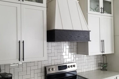 Example of a farmhouse vinyl floor and brown floor kitchen design in Other with a single-bowl sink, shaker cabinets, white cabinets, quartzite countertops, white backsplash, subway tile backsplash, stainless steel appliances and white countertops