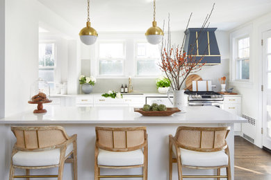 Transitional galley kitchen in New York with a drop-in sink, shaker cabinets, white cabinets, stainless steel appliances, dark hardwood floors, a peninsula, brown floor and white benchtop.