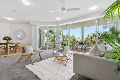 Photo of a mid-sized beach style open concept living room in Sunshine Coast with white walls, carpet, no tv and grey floor.