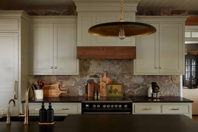 Eat-in kitchen - large traditional l-shaped medium tone wood floor and brown floor eat-in kitchen idea in Toronto with a farmhouse sink, flat-panel cabinets, gray cabinets, granite countertops, multicolored backsplash, stone slab backsplash, black appliances, an island and black countertops