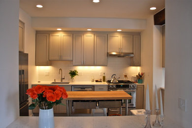 Example of a small transitional u-shaped kitchen design in Boston with recessed-panel cabinets, beige cabinets, quartz countertops, an island, an undermount sink, white backsplash, subway tile backsplash and stainless steel appliances