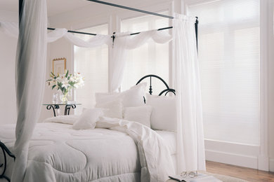 Mid-sized elegant master medium tone wood floor and brown floor bedroom photo in New York with white walls and no fireplace
