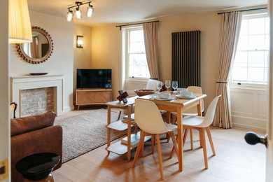 This is an example of a small traditional cream and black open plan living room curtain in Kent with yellow walls, laminate floors, a standard fireplace and beige floors.