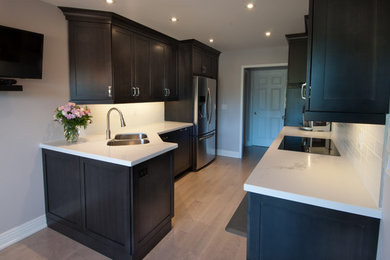 Inspiration for a small modern galley separate kitchen in Toronto with a double-bowl sink, shaker cabinets, dark wood cabinets, white splashback, subway tile splashback, stainless steel appliances, dark hardwood floors, no island and marble benchtops.