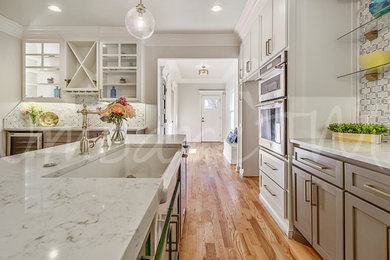 Inspiration for a mid-sized timeless laminate floor and brown floor kitchen pantry remodel in Other with a farmhouse sink, shaker cabinets, beige cabinets, quartz countertops, beige backsplash, subway tile backsplash, stainless steel appliances, an island and beige countertops