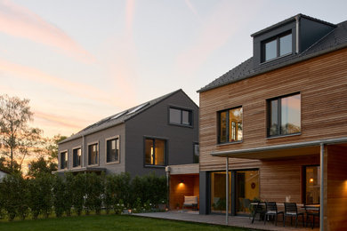 Mittelgroßes, Zweistöckiges Modernes Haus mit brauner Fassadenfarbe, Satteldach, Ziegeldach, schwarzem Dach und Verschalung in München