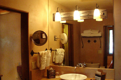 Example of a mid-sized southwest terra-cotta tile powder room design in Albuquerque with raised-panel cabinets, dark wood cabinets, a two-piece toilet, beige walls, a vessel sink and concrete countertops