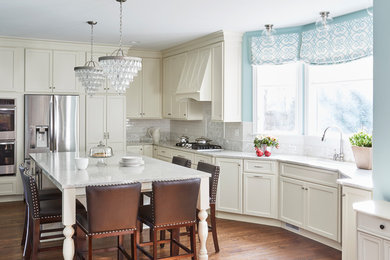 Eat-in kitchen - large traditional l-shaped medium tone wood floor and brown floor eat-in kitchen idea in San Francisco with an undermount sink, flat-panel cabinets, white cabinets, quartz countertops, white backsplash, marble backsplash, stainless steel appliances and an island