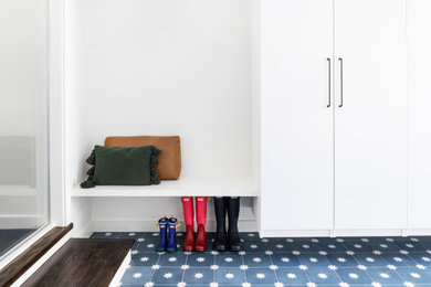 Small trendy concrete floor and blue floor mudroom photo in Boston with white walls