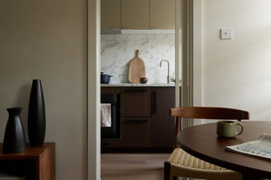 Design ideas for a small contemporary l-shaped enclosed kitchen in London with an integrated sink, flat-panel cabinets, dark wood cabinets, engineered stone countertops, white splashback, engineered quartz splashback, black appliances, medium hardwood flooring, beige floors and white worktops.