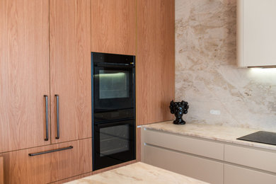 Design ideas for a large scandinavian l-shaped open plan kitchen in Sydney with a single-bowl sink, flat-panel cabinets, medium wood cabinets, marble benchtops, beige splashback, marble splashback, black appliances, light hardwood floors, with island, brown floor and beige benchtop.