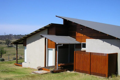 Photo of a large contemporary one-storey beige house exterior with wood siding, a shed roof and a metal roof.